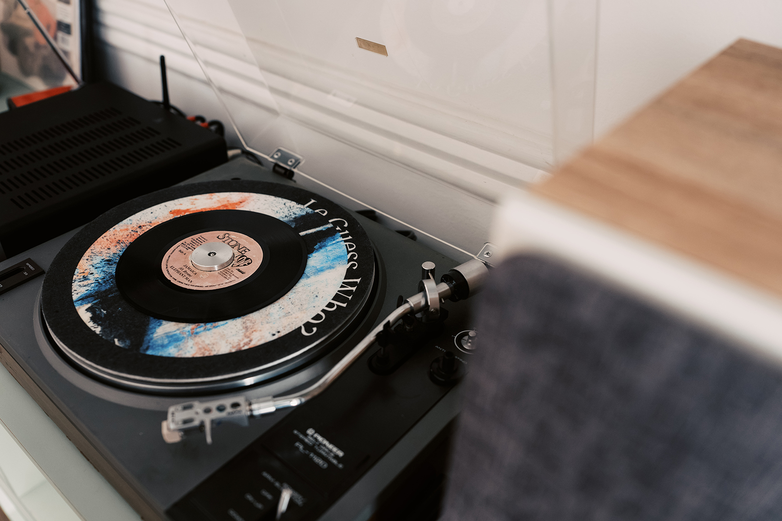 A photo of a record player. On the record player lays a slipmat that says "Le Guess Who?"